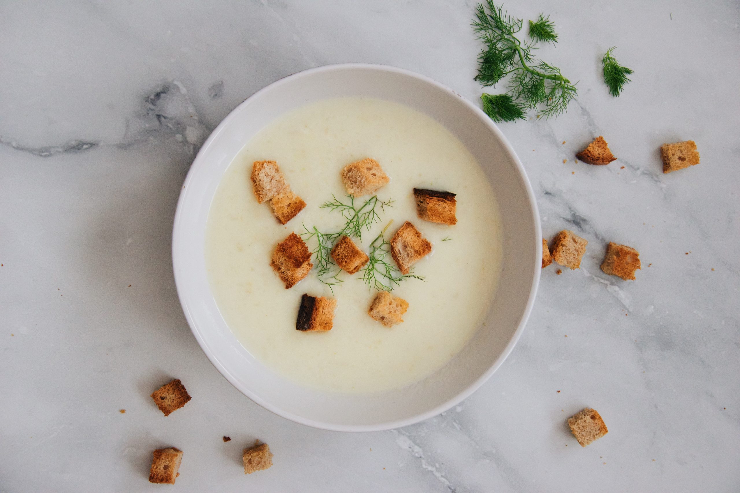 A Romanian bowl of tripe soup with croutons and dill