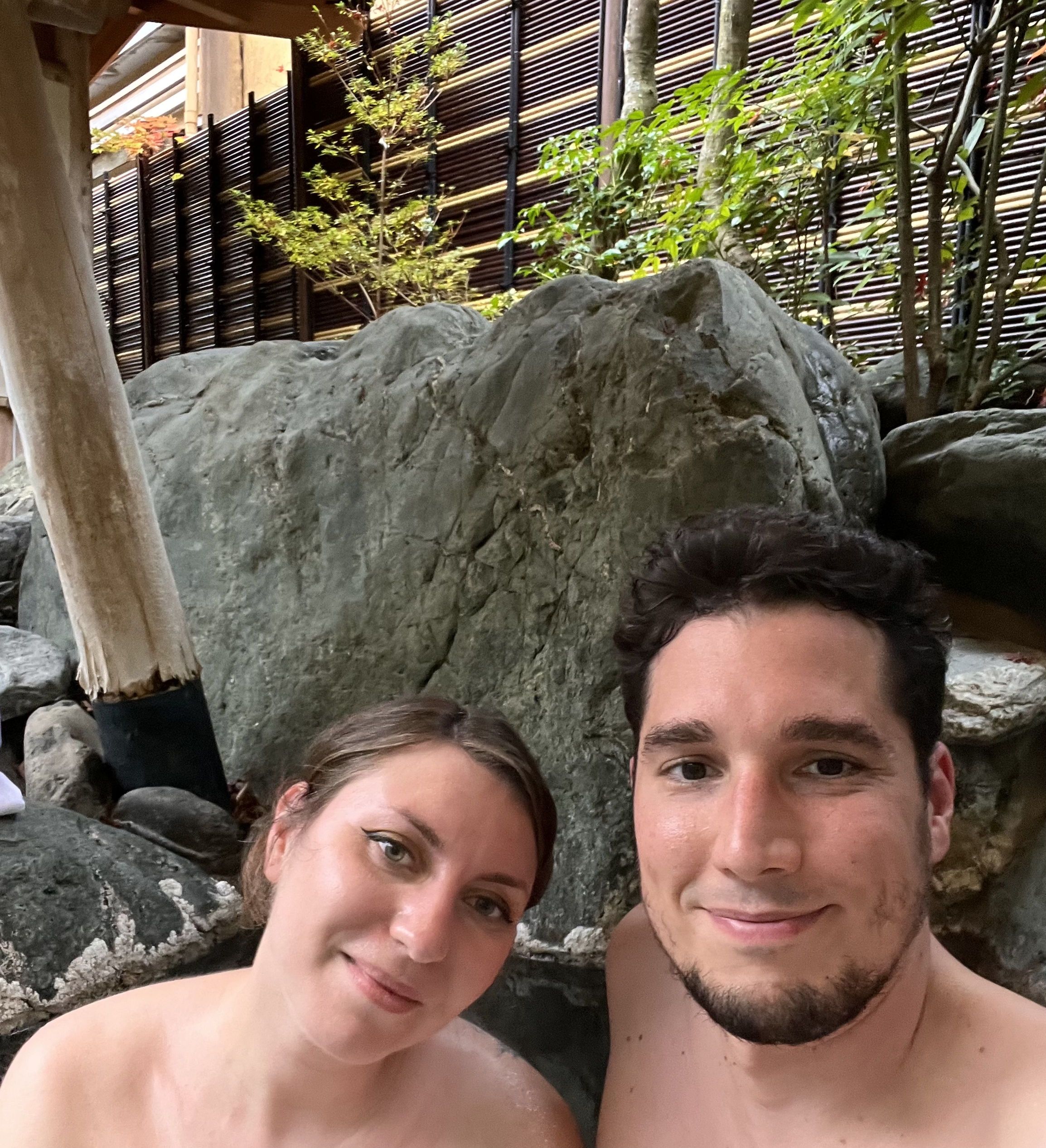 Cory and Greg from You Could Travel in a private onsen with Cory's tattoo visible on her shoulder and back