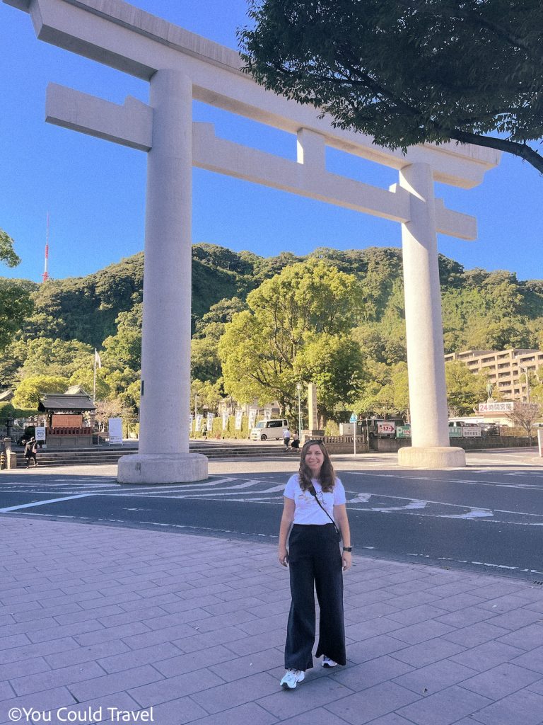 Cory from You Could Travel in Kagoshima Japan with a large torii behind