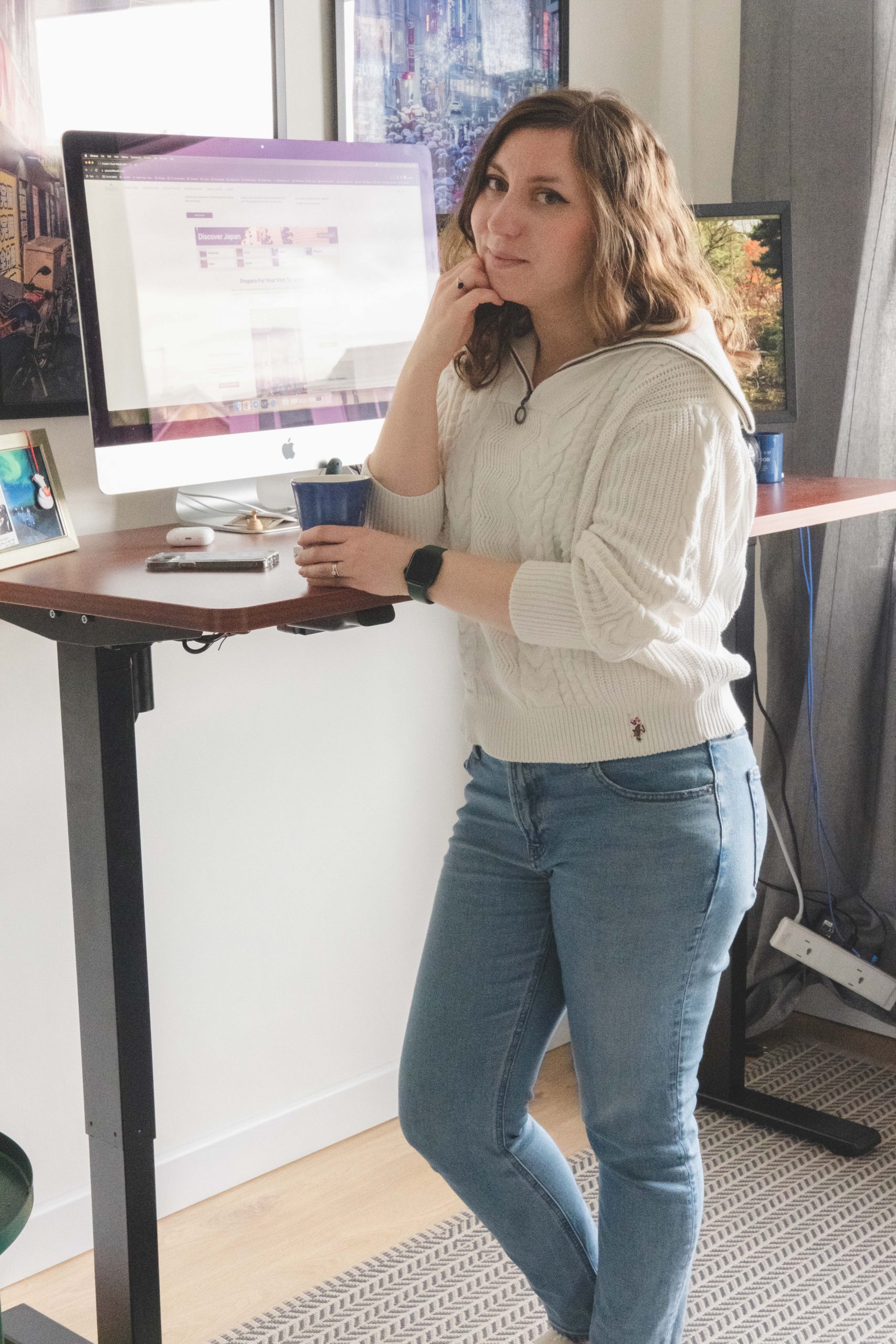 Cory smiling with a coffee at her Flexispot standing desk