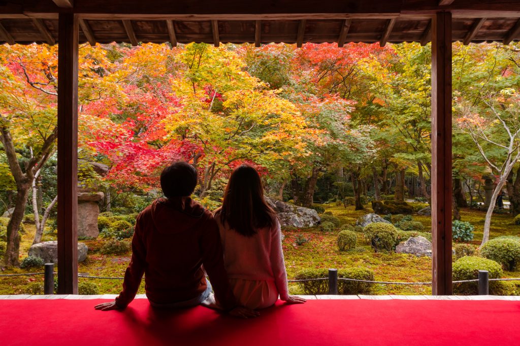 Young couple looking at a beautiful autumn garden in Japan