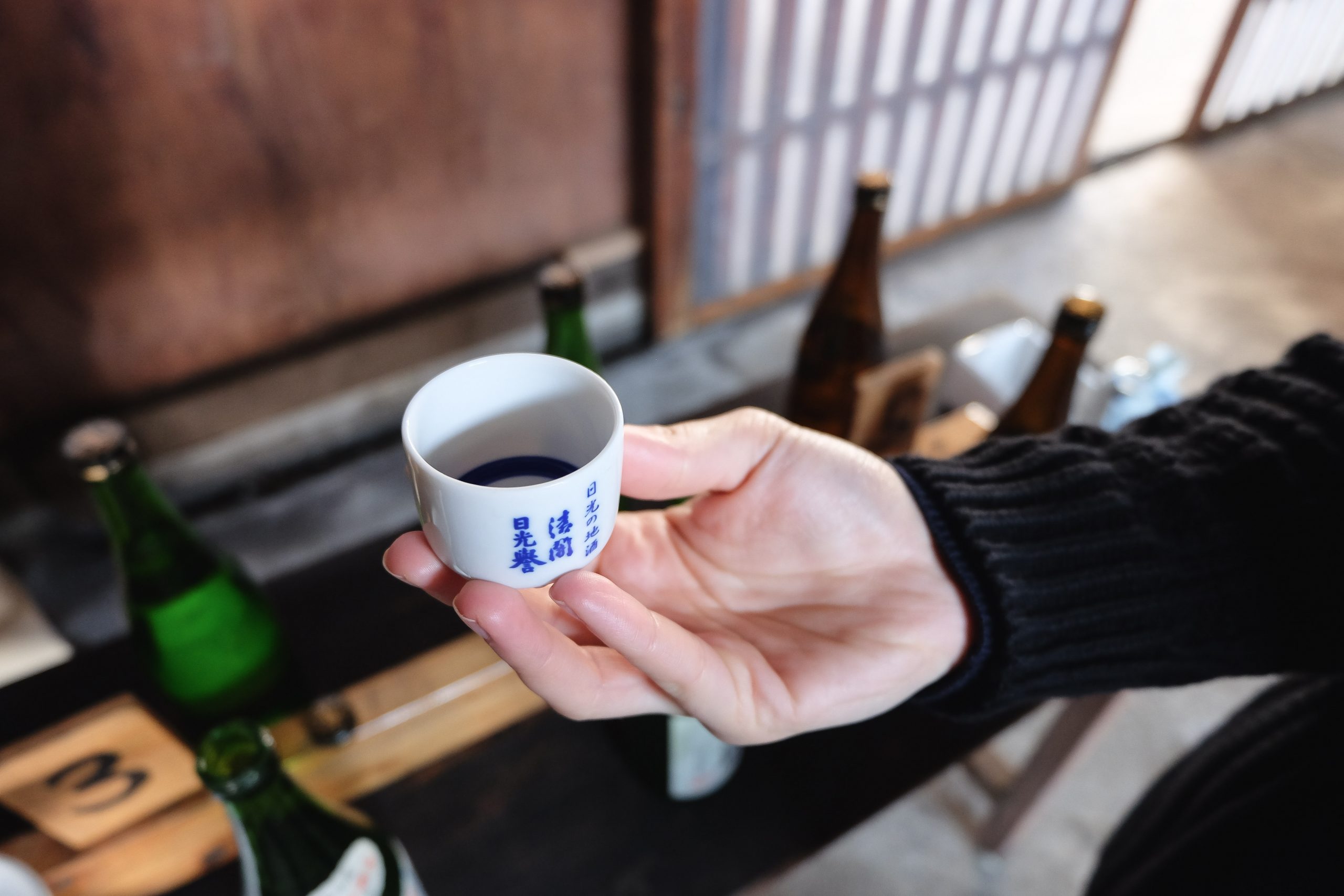 Cory is holding a sake cup at Watanabe Sake Brewery in Nikko