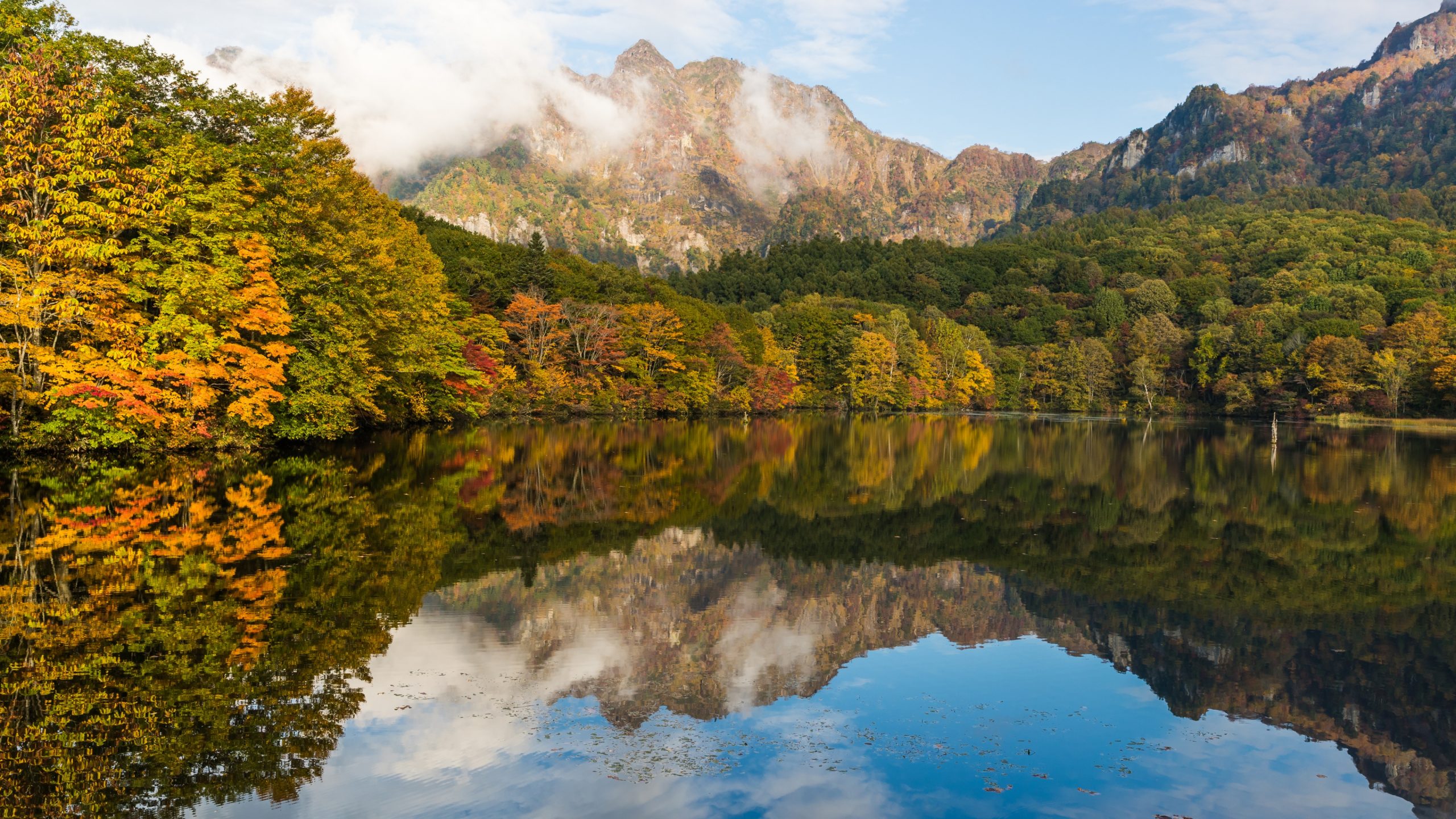 Kagami pond in the autumn, with its vibrant reflection Lake Kagami and surrounding forests and mountains