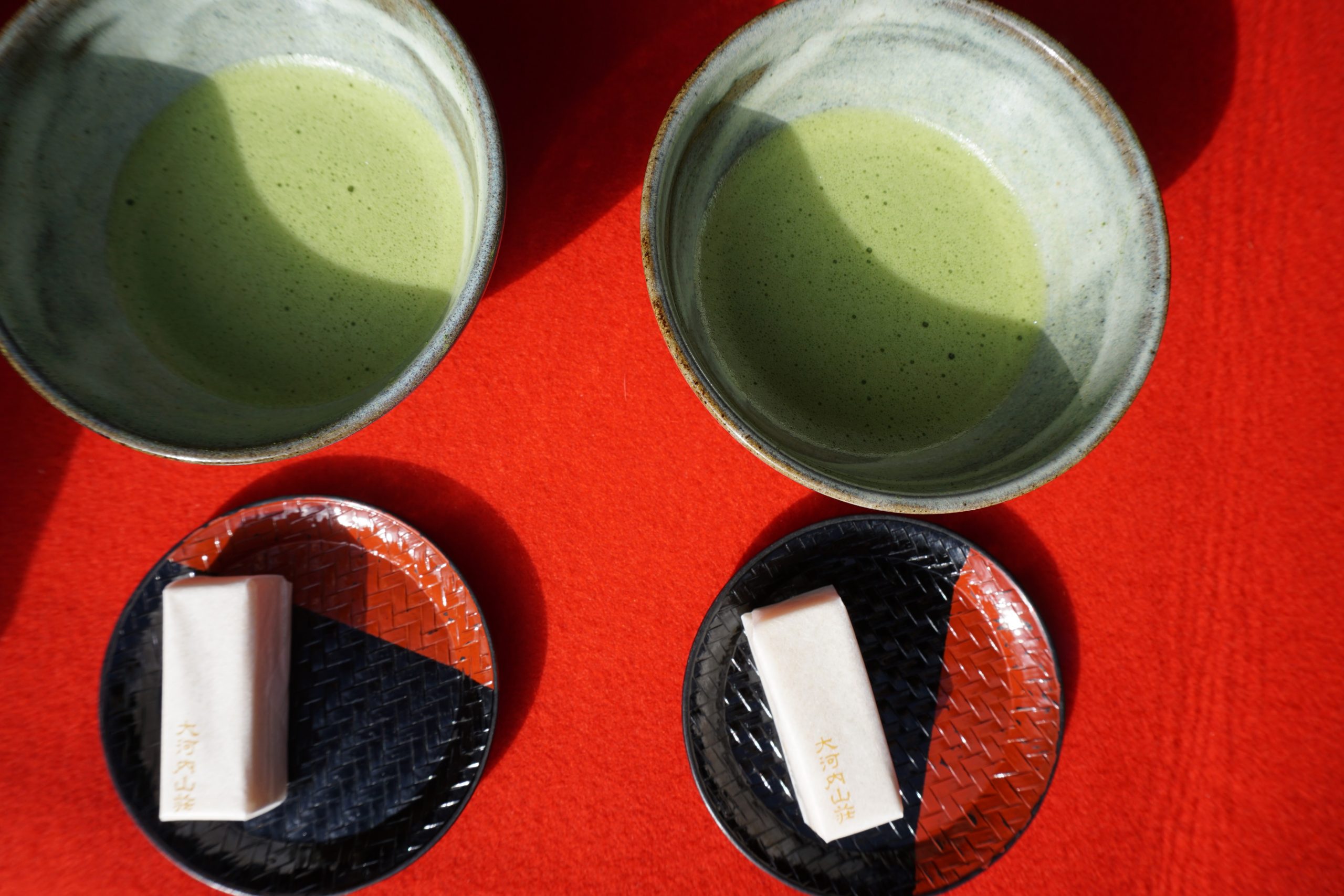 Two bowls of Japanese matcha tea served with small wagashi