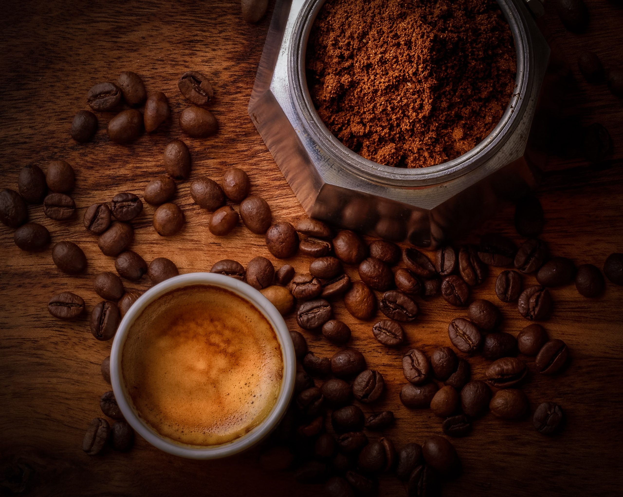 Stages of coffee from coffee beans through ground coffee to a cup of ready made coffee