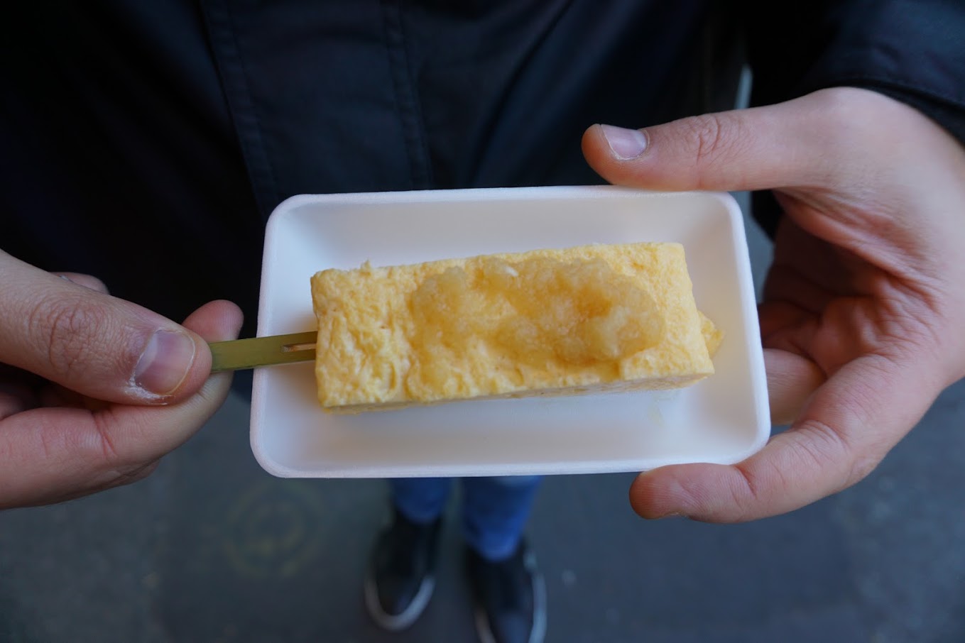 Greg from You Could Travel holding Tamagoyaki purchased at Tsukiji Market