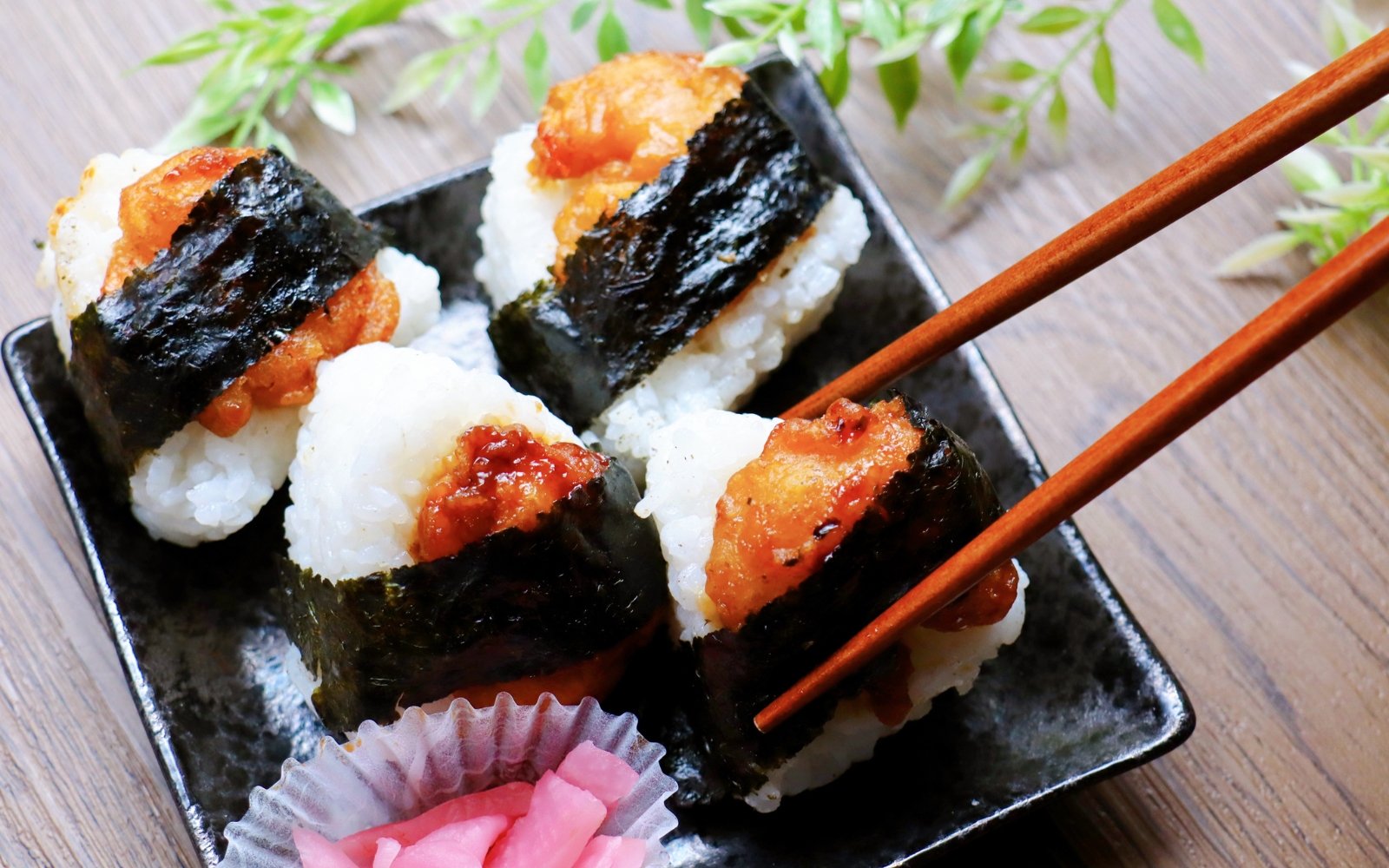 A rice ball with shrimp tempura wrapped in nori, known as tenmusu