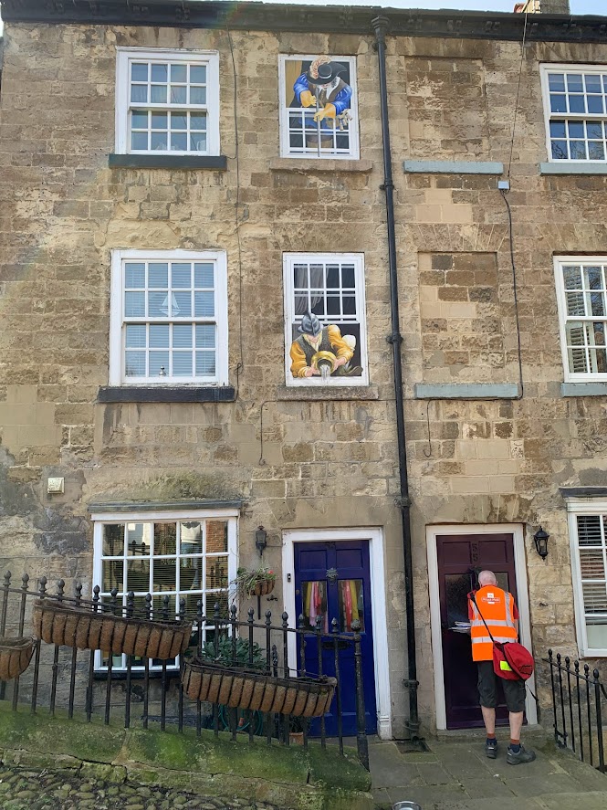 The postman delivering letters in a cottage with window paintings in Knaresborough