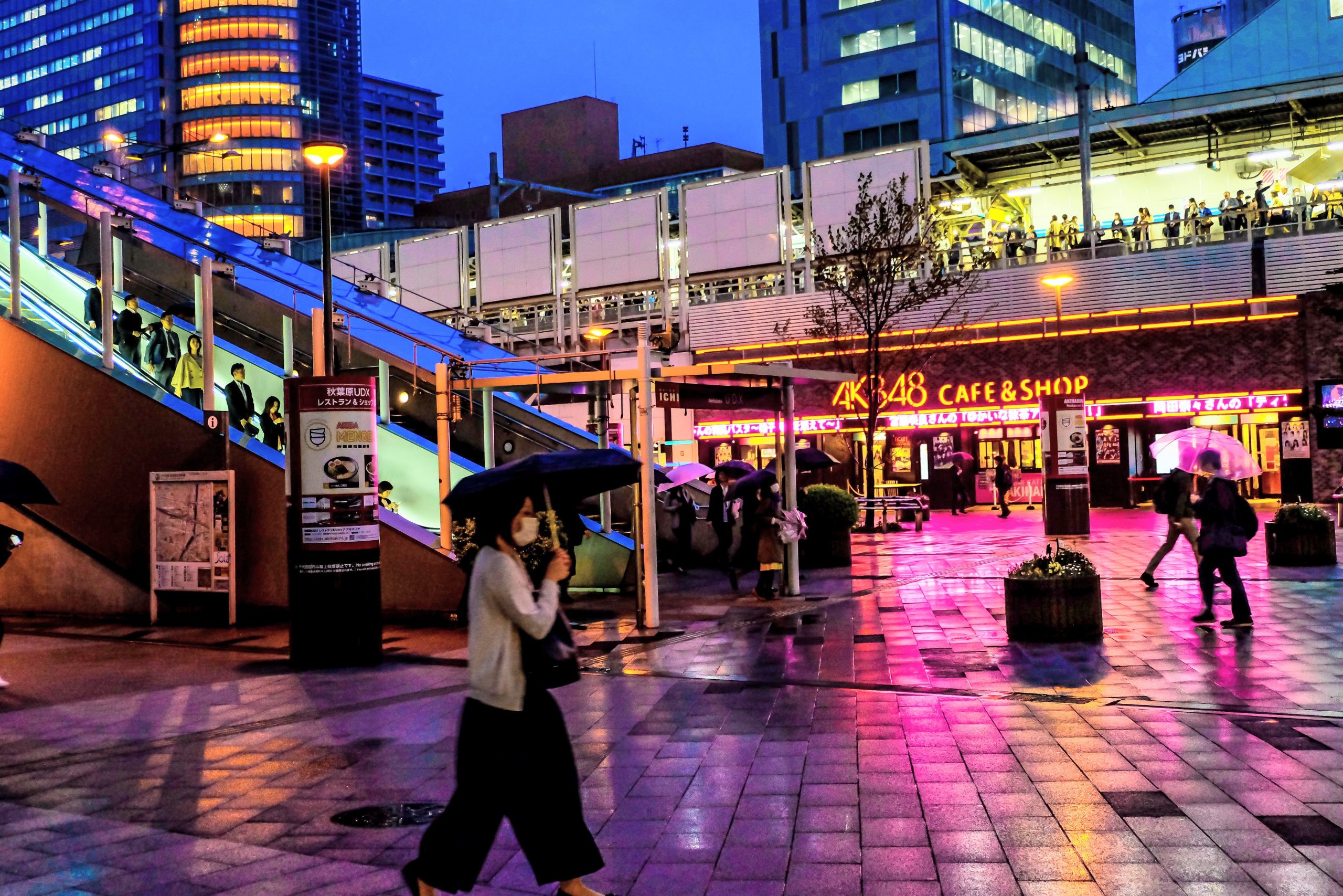 Woman walking in front of the Tokyo Akihabara Station on a rainy evening