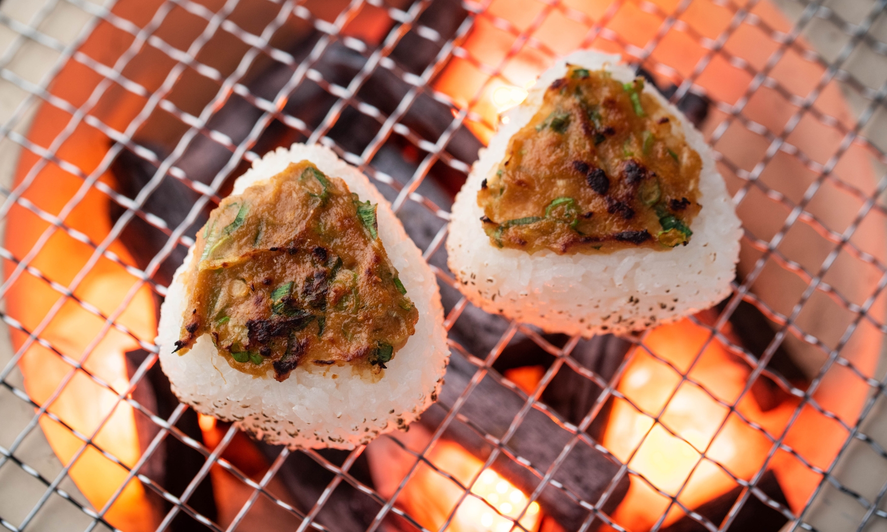 Yaki onigiri street food Yaki onigiri with miso topping being prepared on a grill