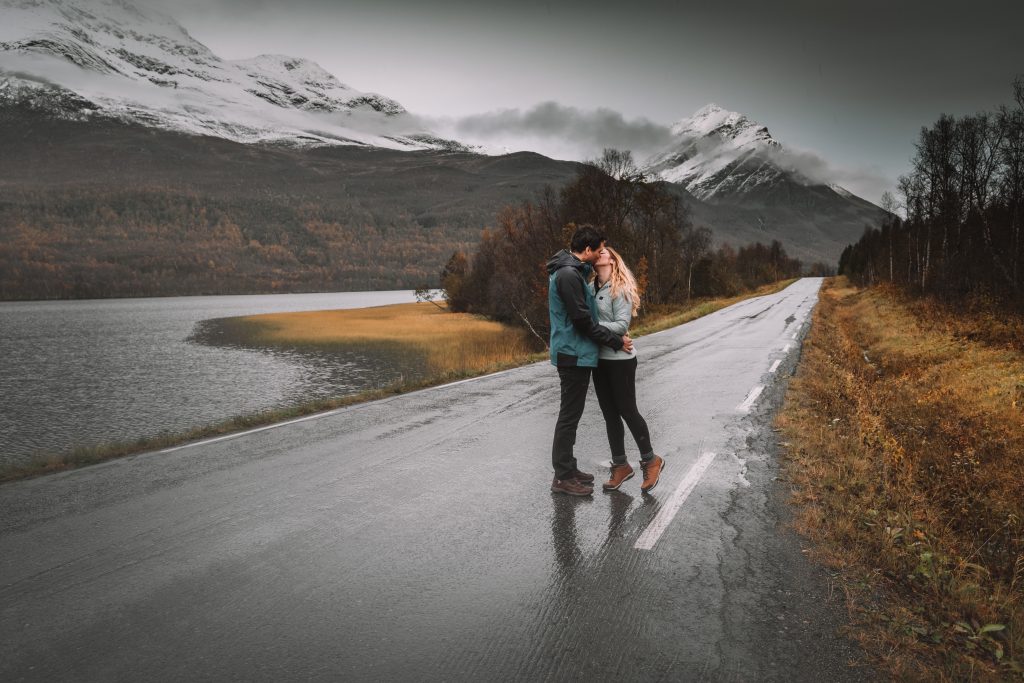 Cory and Greg from You Could Travel hugging and kissing on an empty road in Tromso Norway